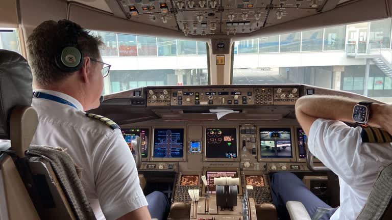 Twee piloten in de cockpit van een Boeing 777, met verlichte instrumentenpanelen